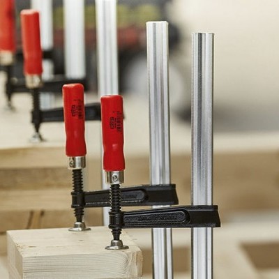 Grampos de aperto vermelhos e metálicos fixados em madeira