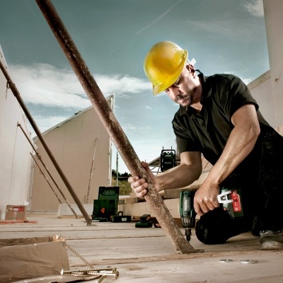 Homem com capacete amarelo a trabalhar numa construção de madeira