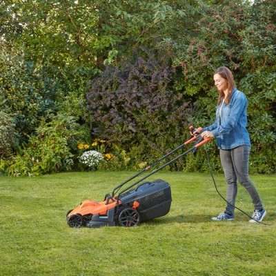 Mulher a cortar relva com cortador de relva elétrico laranja e preto num jardim