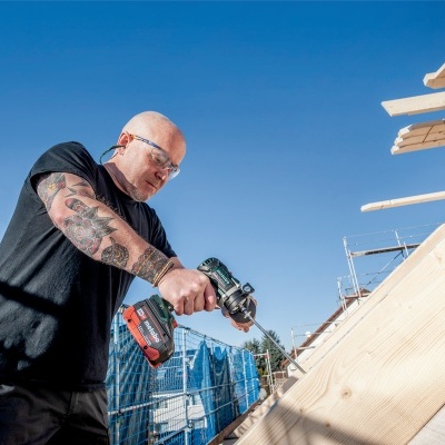 Homem a usar furadeira elétrica em madeira ao ar livre