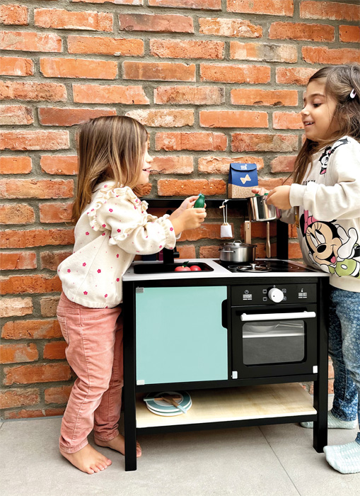 Cozinha Infantil Estilo INDUSTRIAL Duas crianças brincam com cozinha de brinquedo de madeira contra parede de tijolos