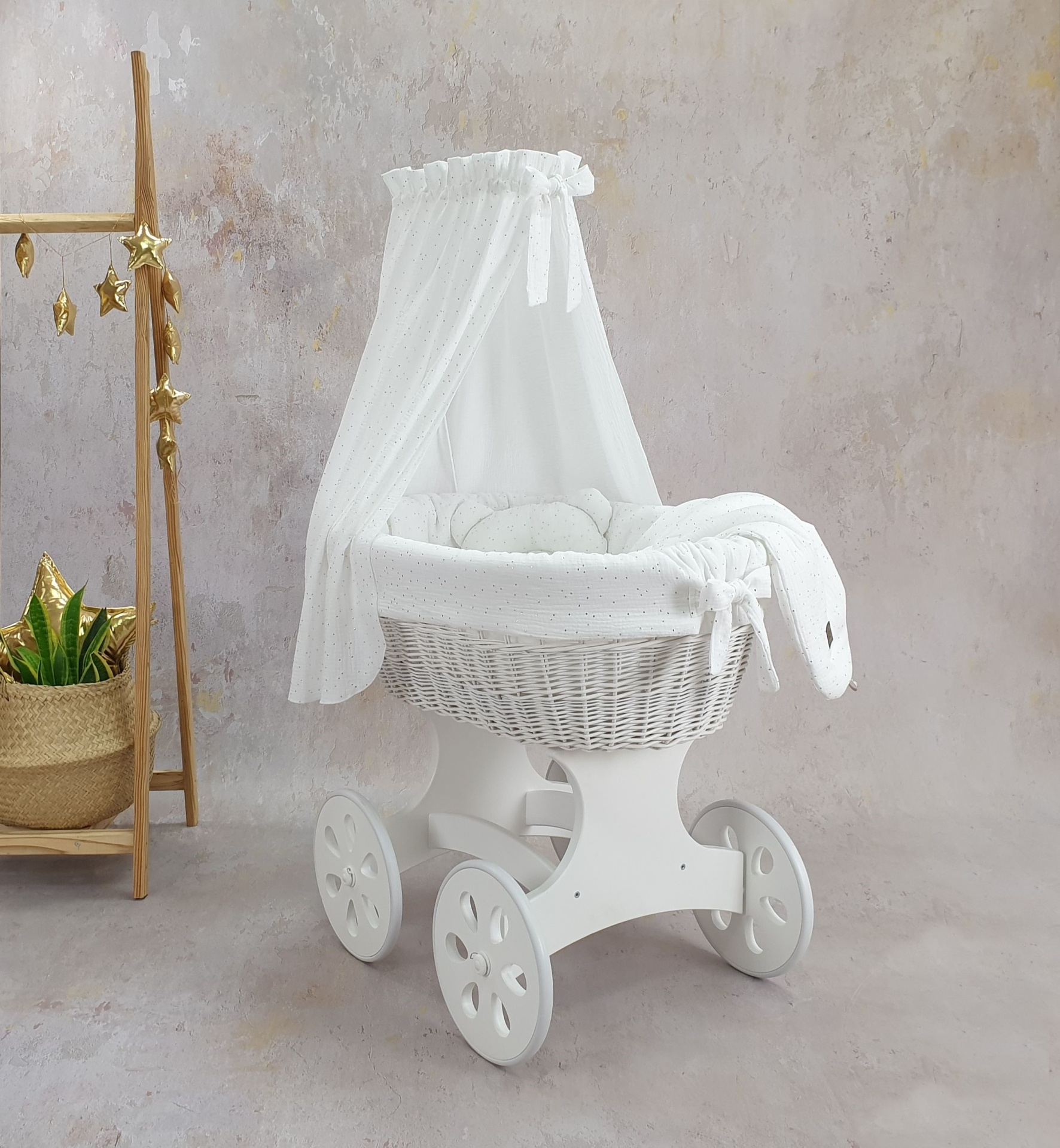 Cesta Moisés de Vime Branco SARA com Roupa de Cama Berço de bebé branco com dossel e almofadas, junto a planta e cabide decorativo