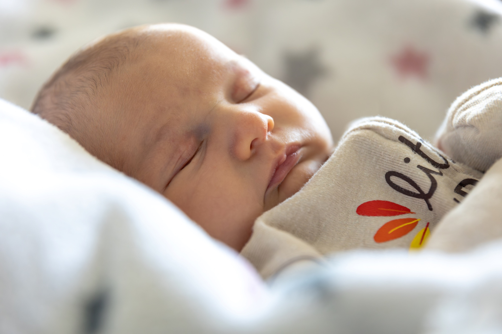 Recém-nascido a dormir com roupa bege e padrão de folhas