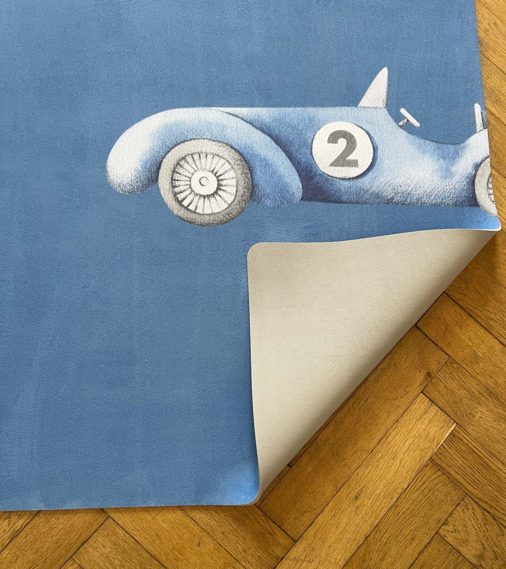 Tapete Educativo ECO Carros de Corrida PRIME Tapete azul com carro de corrida e número 2 sobre chão de madeira