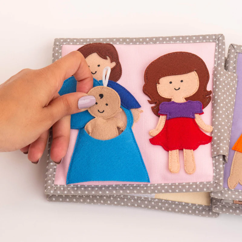 Bebé Feliz – MINI Livro Sensorial de 6 Páginas Livro têxtil infantil com bonecas de feltro colorido e padrão de bolinhas cinza.