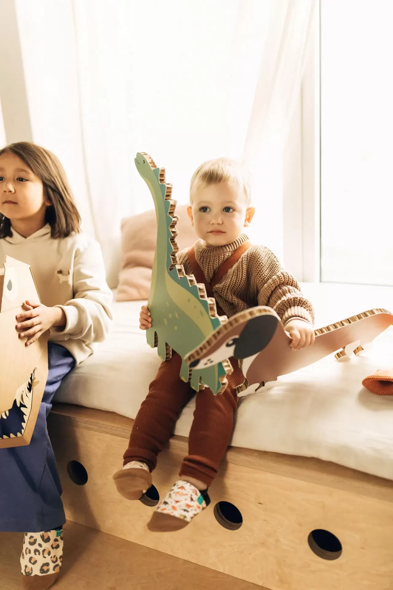 Sapatinhos de Criança em Couro Natural – Dinossauro Marron Crianças com brinquedos de madeira em cama clara