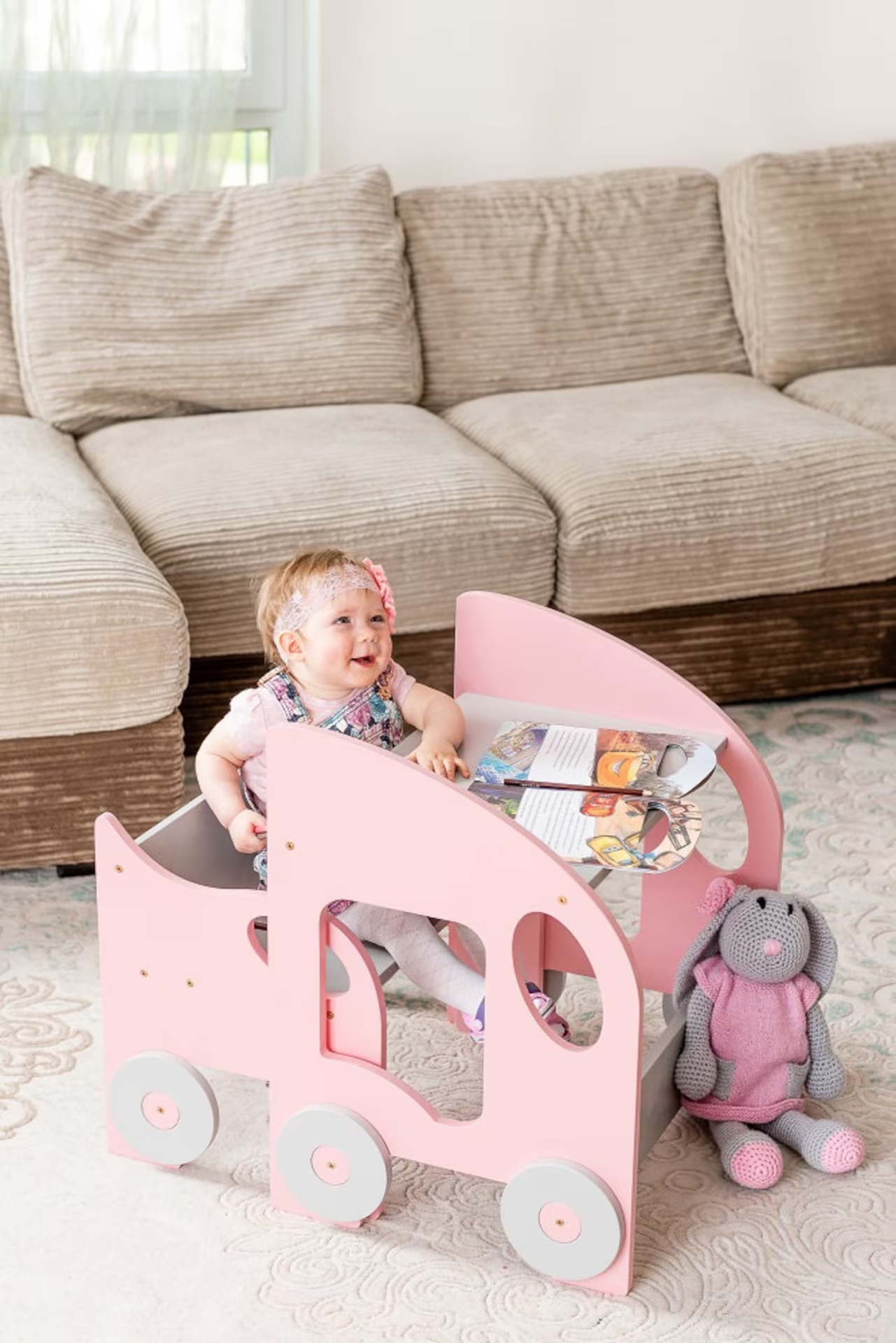 Mesa e Cadeira Infantil MONTESSORI Carrinho de brincar rosa com criança, livros e coelho de malha ao lado