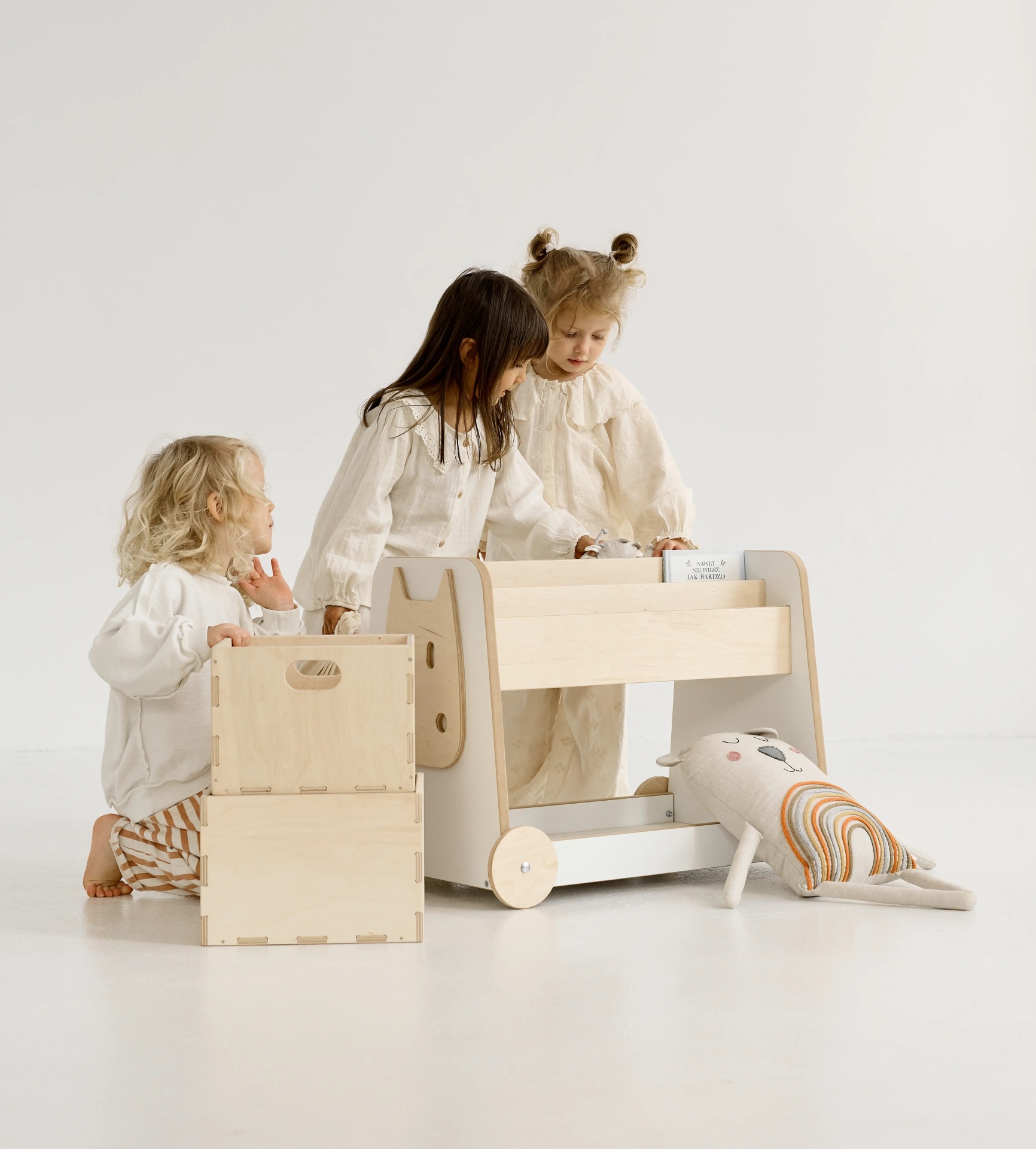 Estante de Madeira Sobre Rodas Crianças brincando com móveis infantis de madeira clara e caixas