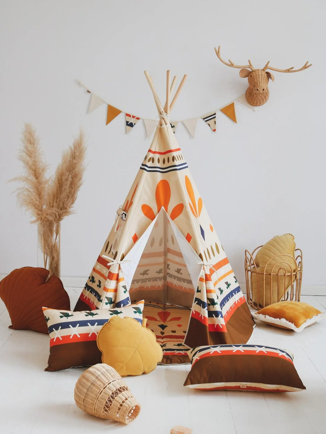 Tenda Tipi NATIVE VIBE Tenda de brincar em tecido com padrão étnico, almofadas coloridas e decoração com cabeça de veado na parede branca