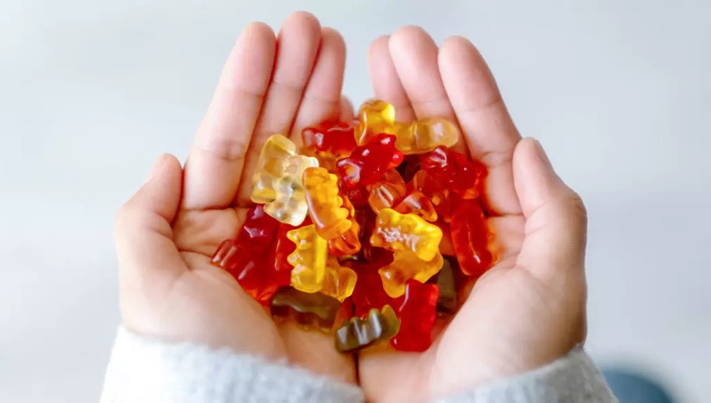 Mãos segurando gomas de ursinho coloridas