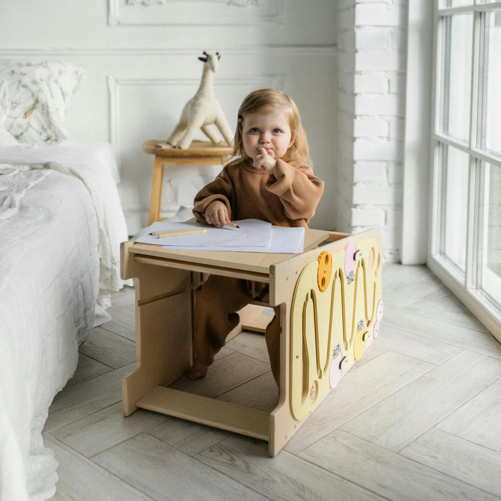 Torre de Aprendizagem Multifuncional 5 em 1 Criança a desenhar numa mesa infantil de madeira com painéis coloridos