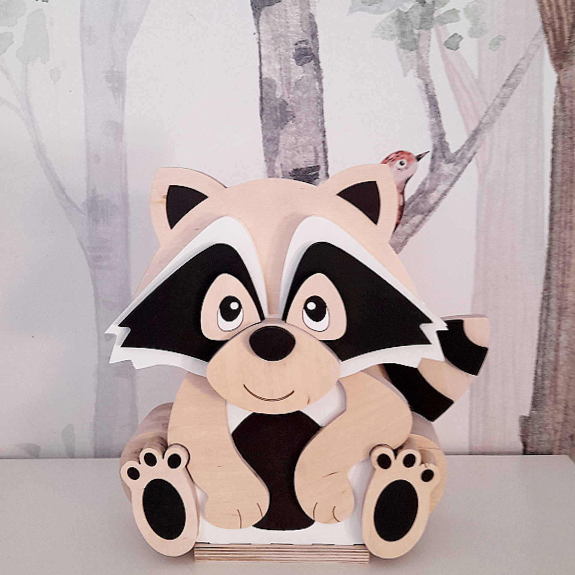 Candeeiro Guaxinim de Madeira Controlado por SMARTPHONE Figura decorativa de guaxinim em madeira sobre superfície branca com fundo de árvores e pássaro no papel de parede.