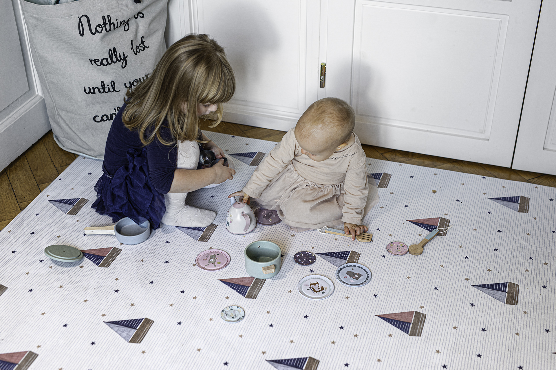 Tapete Ecológico PEQUENO MARINHEIRO Tapete infantil branco com padrão de balões coloridos, crianças brincando sentadas no tapete