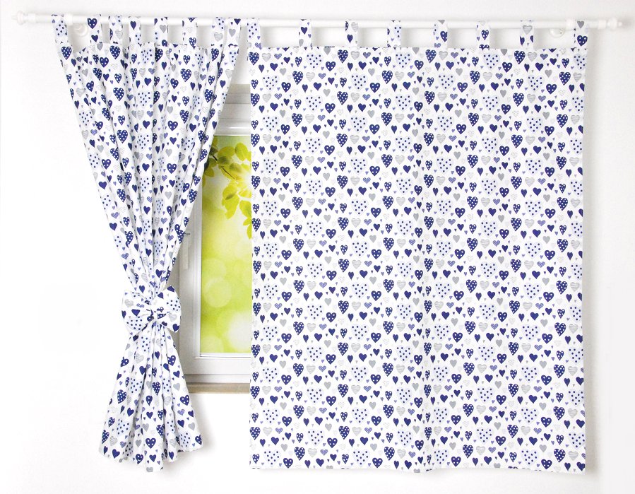 Cortinados Infantis Corações Conjunto de cortinas brancas com corações azuis e cinzentos num ferro branco em frente a uma janela.