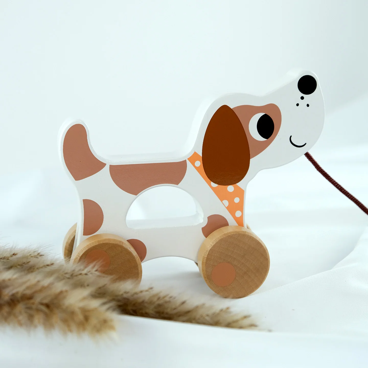 Caixa de Brinquedos Educativos Montessori 18–24 Meses em Madeira Brinquedo de madeira em forma de cão branco com manchas castanhas e rodas de madeira.