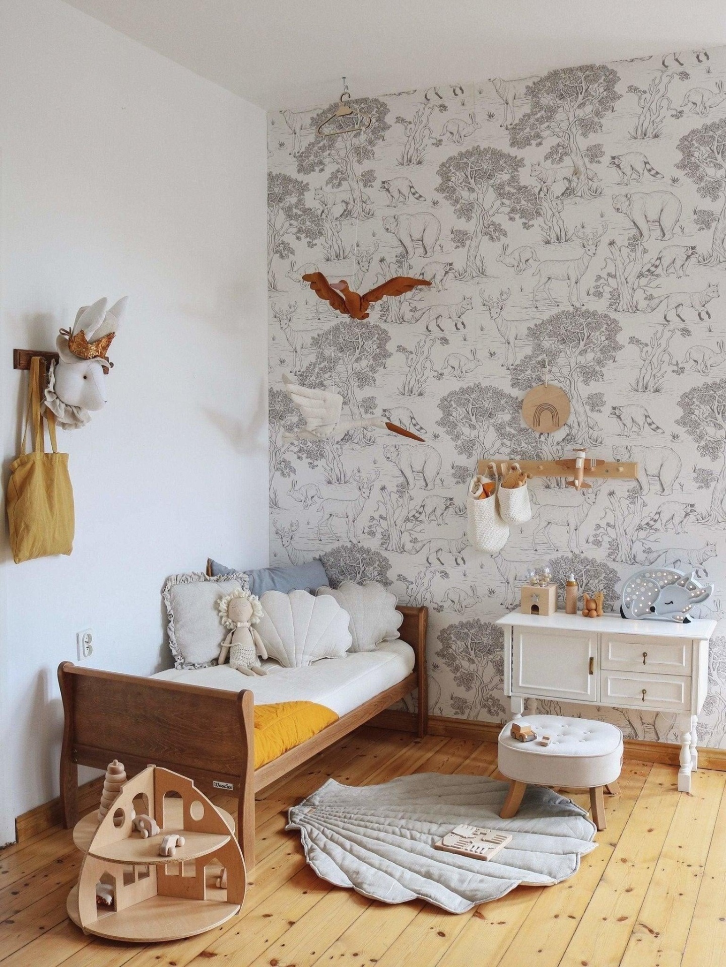 Tapete de Linho CONCHA Quarto infantil com cama de madeira, almofadas, tapete cinza, papel de parede com padrão, móveis brancos e brinquedos de madeira
