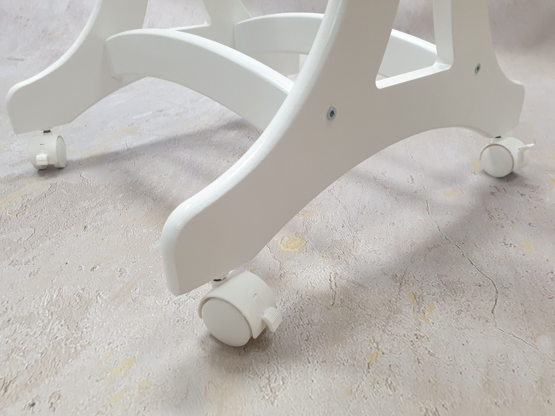 Cesta Moisés de Vime Branco EMMA com Roupa de Cama Base branca com rodas sobre pavimento cinzento texturizado