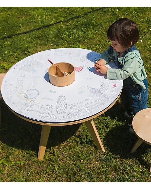 Recarga de Folhas para Colorir - Coelhinhos Mesa redonda branca com desenhos para colorir, criança a pintar, mesa com pernas de madeira clara na relva.