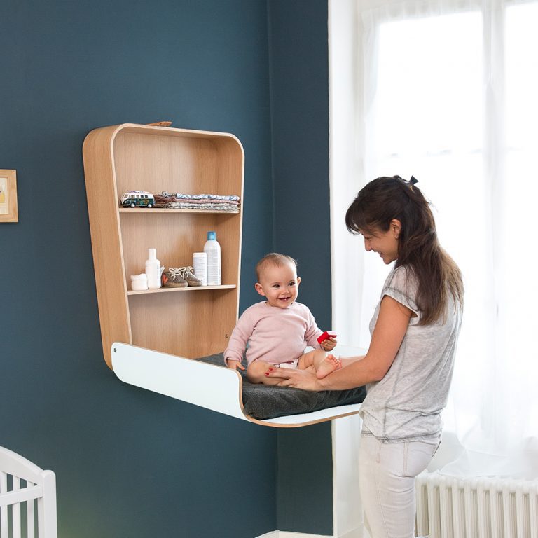 Trocador de Fraldas NOGA para Parede Mudar de fraldas de madeira clara e branca com prateleiras embutidas na parede azul com mulher e bebê