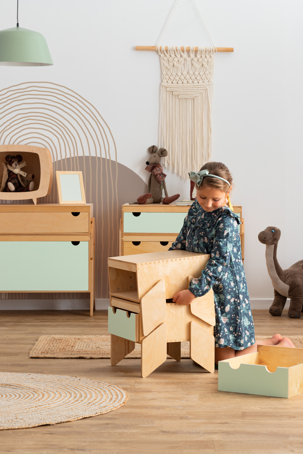 NINO 2 Móvel Modular para Crianças Menina a brincar com móvel infantil de madeira clara e gavetas verdes numa sala infantil decorada