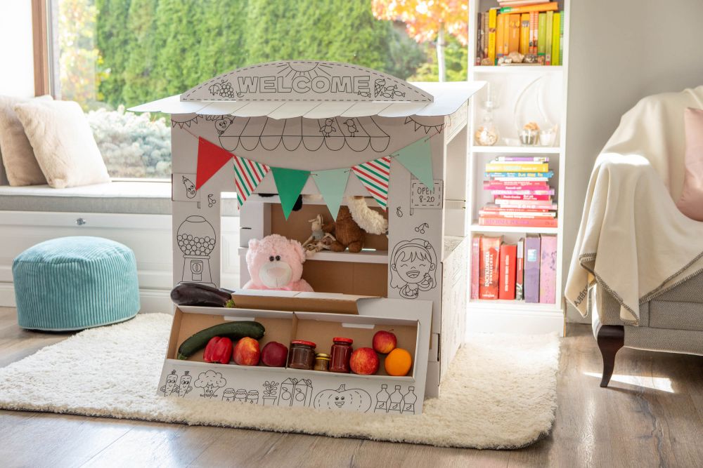 Minimercado para Colorir Casinha de brincar de cartão com decoração e frutas falsas num quarto acolhedor.