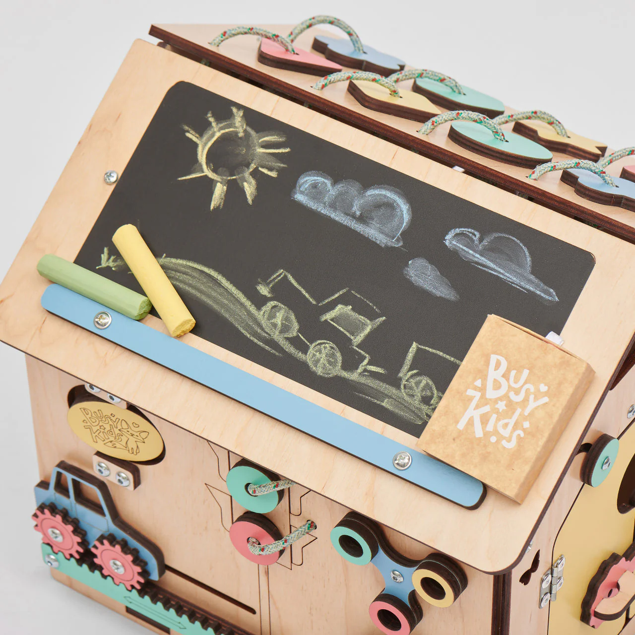 Mini Casa Educacional de Madeira – Método Montessori Brinquedo educativo de madeira com quadro-negro e giz desenhando um trator, sol e nuvens.