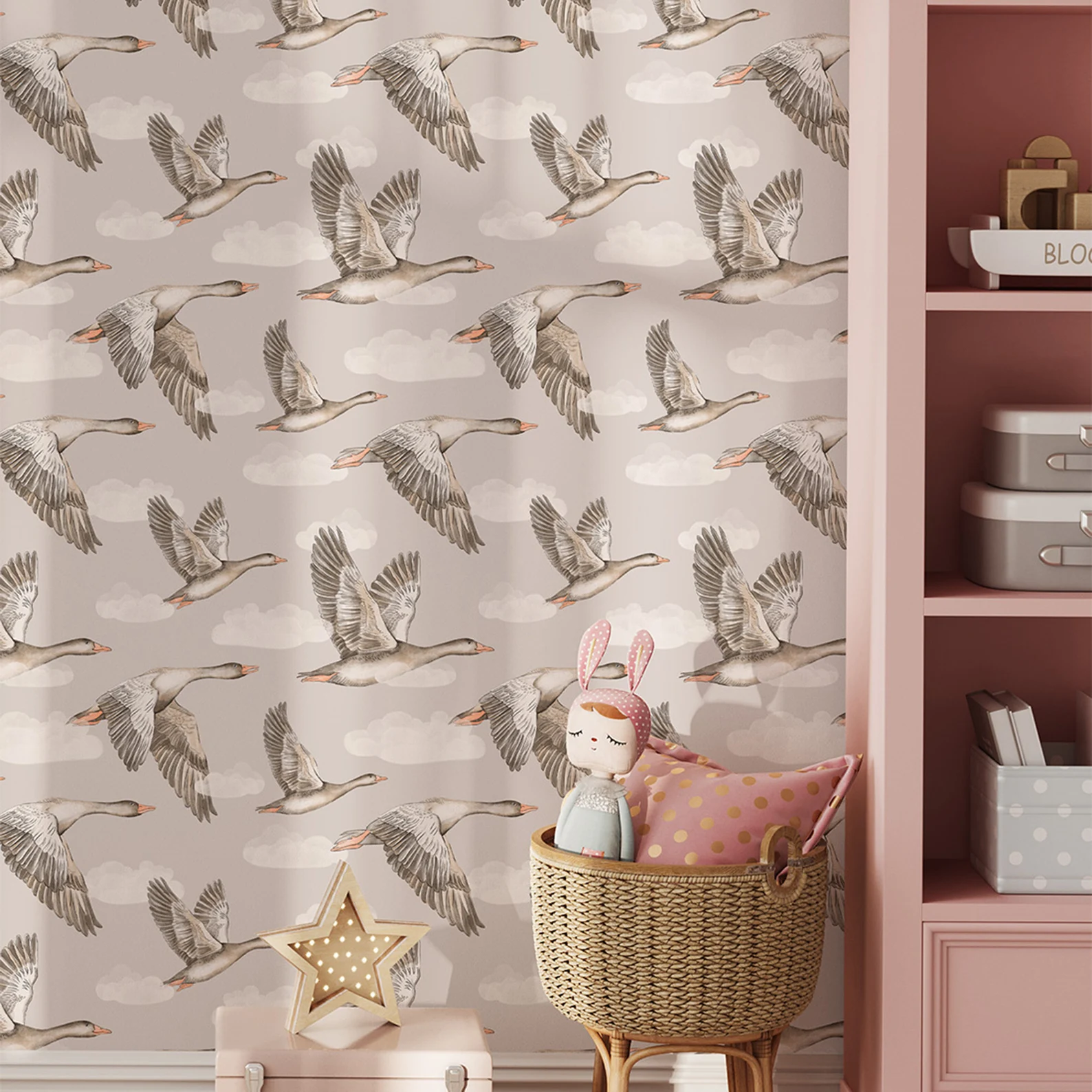 Papel de Parede Infantil Gansos Bege Papel de parede com gansos voando e nuvens, prateleira rosa e cesto de vime com almofada e boneca