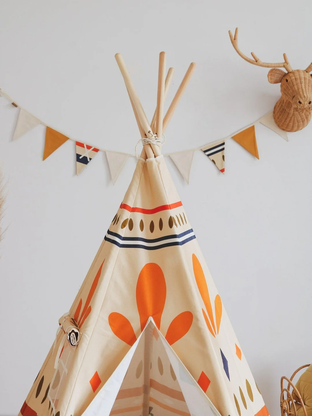 Tenda Tipi NATIVE VIBE Tenda tipi de tecido decorada com padrões laranja e azul com bandeirolas coloridas e cabeça de veado na parede