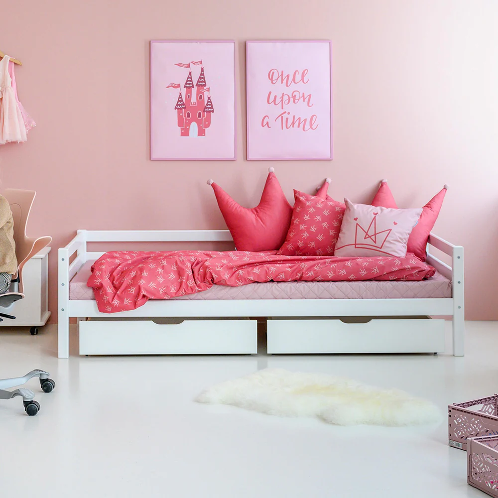 Almofadas Decoração Princesa Cama infantil branca com almofadas e edredão rosa e duas molduras decorativas rosa na parede