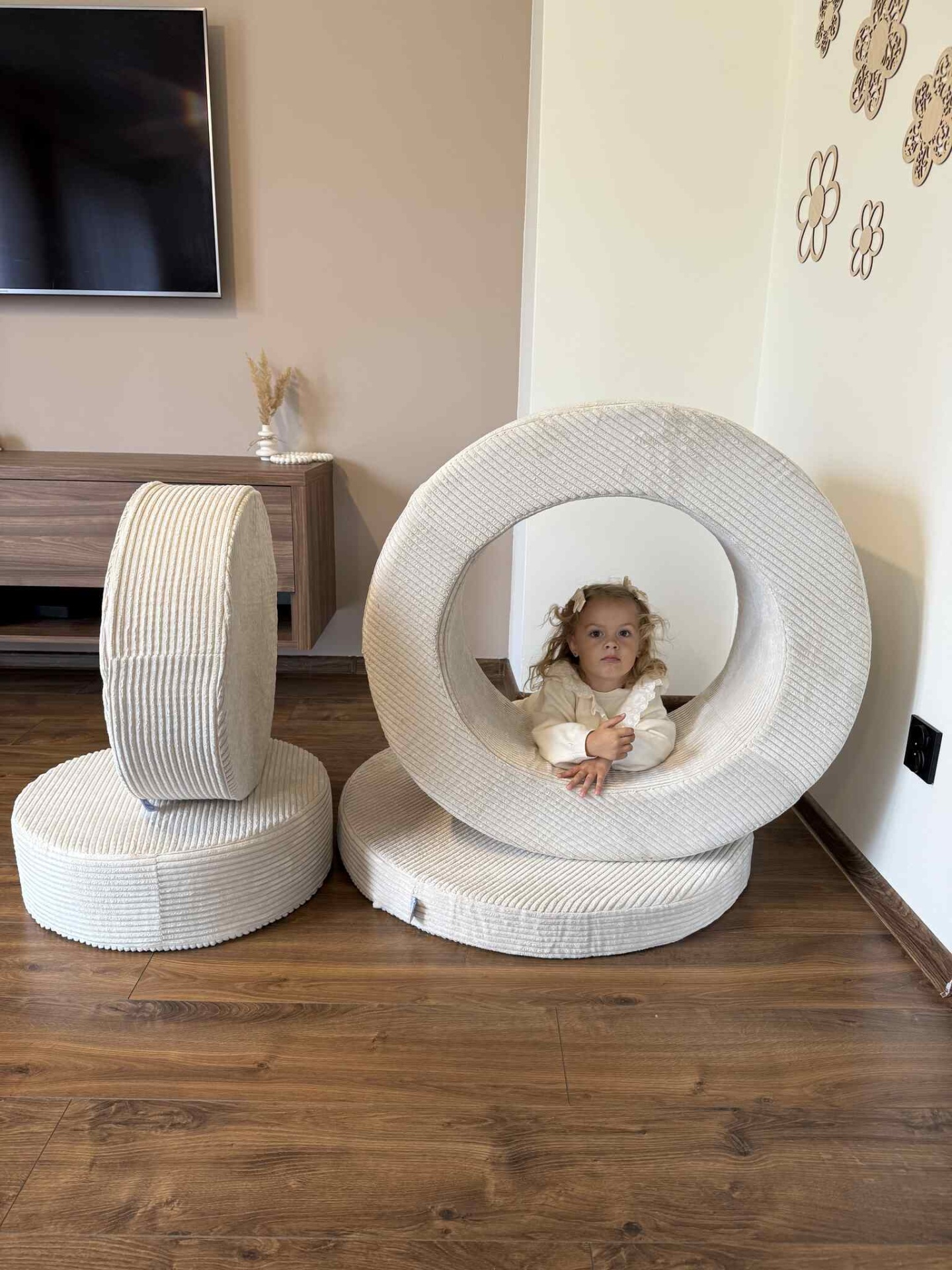 Conjunto Pufe Modular em Veludo Cotelê Bege Almofadas cilíndricas e circulares creme com criança dentro da almofada circular