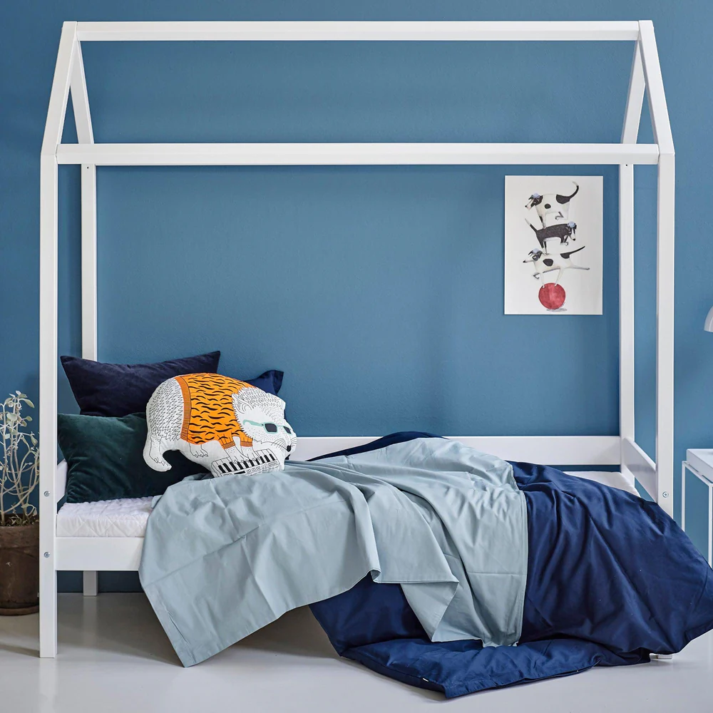 Cama Infantil Casinha Eco Conforto 70x160 Cama branca em forma de casinha com roupa de cama azul e almofada decorativa de urso e parede azul com quadro de cães