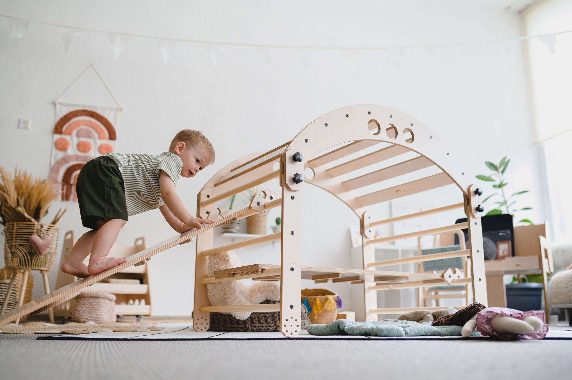 Quarto Montessori: Como Mobiliá-lo e Como Deve Ser Criança a brincar numa estrutura de madeira clara num quarto