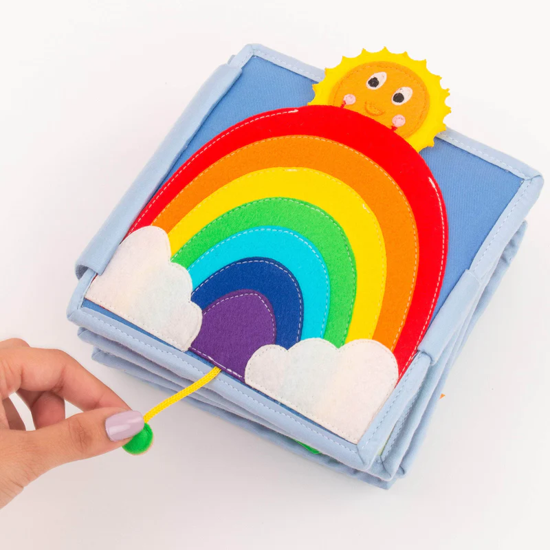 Arco Íris - Mini Livro Sensorial de 6 Páginas Livro sensorial infantil de tecido com arco-íris colorido e sol sorridente