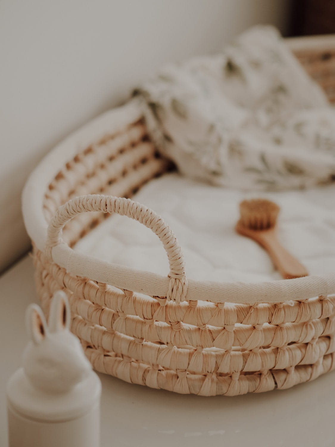 Cesto Fraldário de CASCA de MILHO Cesto de verga com almofada branca e escova de madeira, garrafa branca com tampa de coelho.