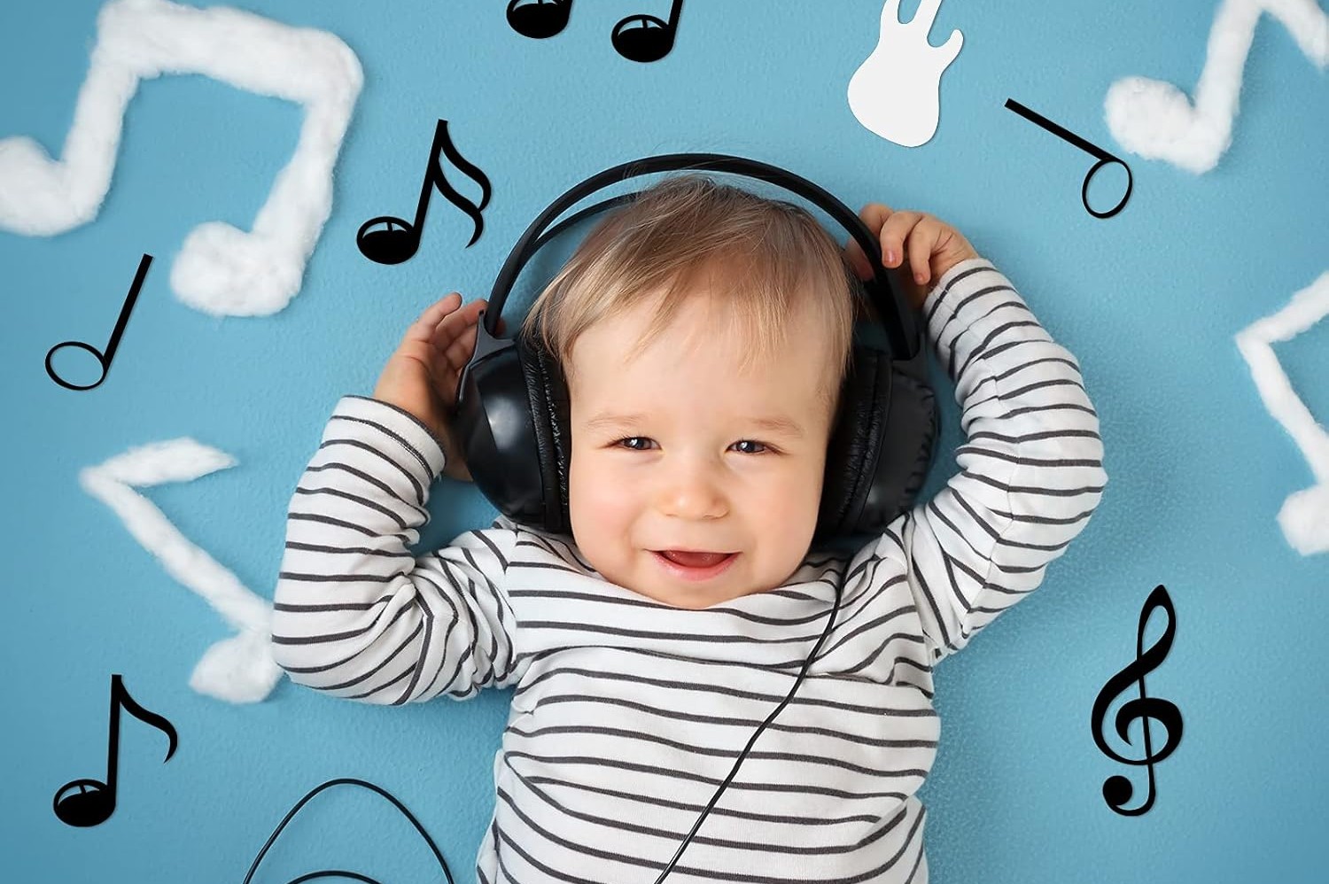 A Importância de Ouvir Música com as Crianças Bebé com auscultadores a ouvir música com fundo azul e notas musicais