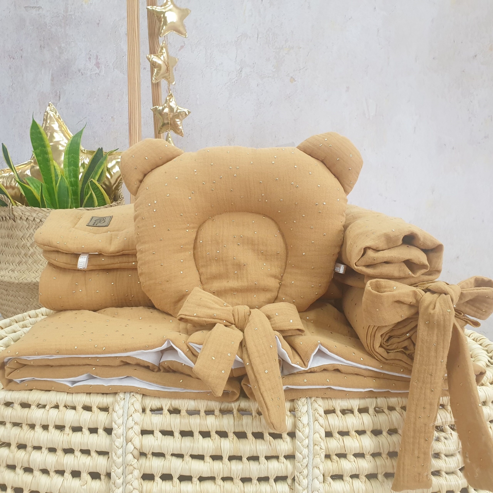 Cesta Moisés de Vime Branco EMMA com Roupa de Cama Almofadas castanho claro para bebé sobre cesta de verga com plantas e estrelas douradas ao fundo