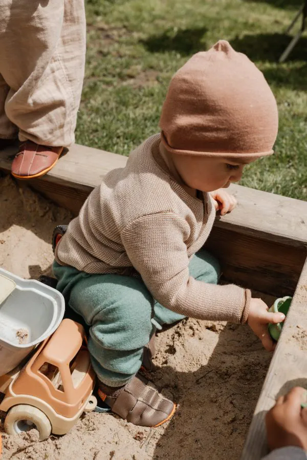 Sandália Infantil Rosa-Velho Criança sentada numa caixa de areia a brincar com brinquedos