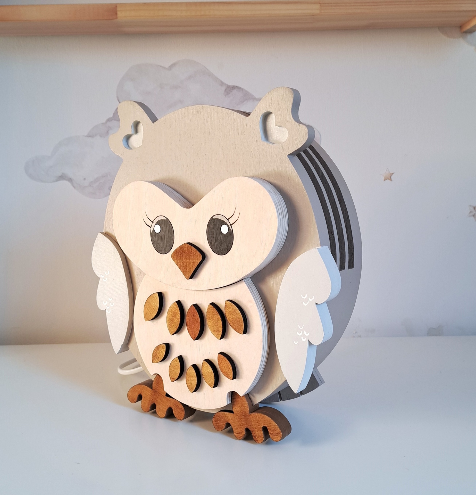 Candeeiro Coruja de Madeira Controlado por SMARTPHONE Cofre de madeira em forma de coruja com pintura bege, branco e castanho em fundo com nuvens e estrelas.