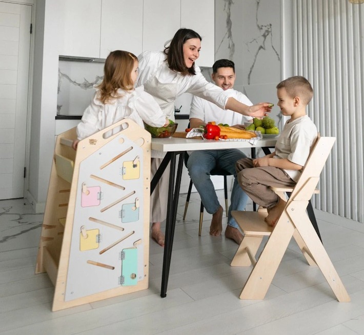 Mesa branca com pernas pretas e cadeiras de madeira clara numa cozinha moderna