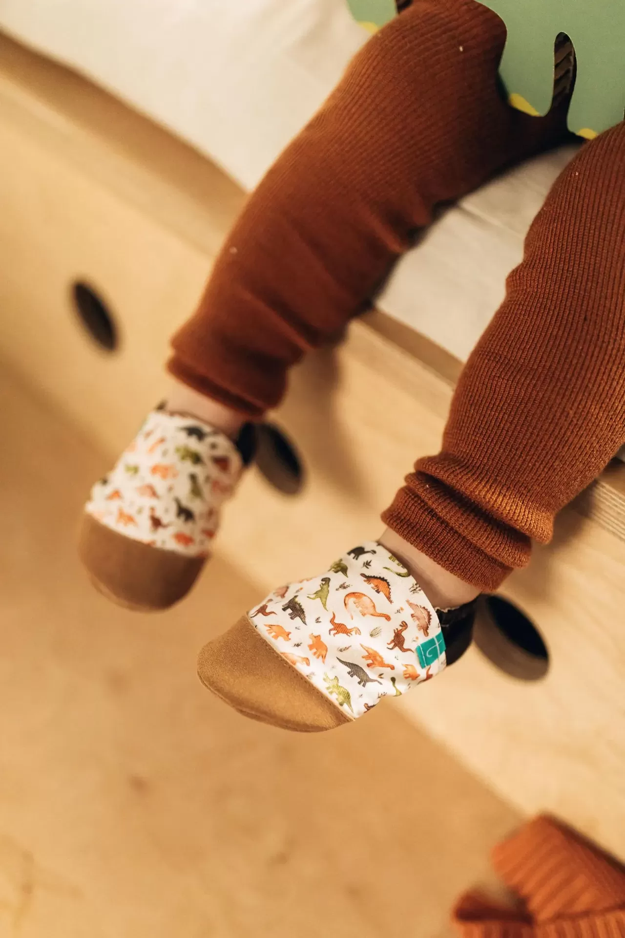 Sapatinhos de Criança em Couro Natural – Dinossauro Marron Sapatinhos de bebé com padrão de dinossauros e calças castanhas