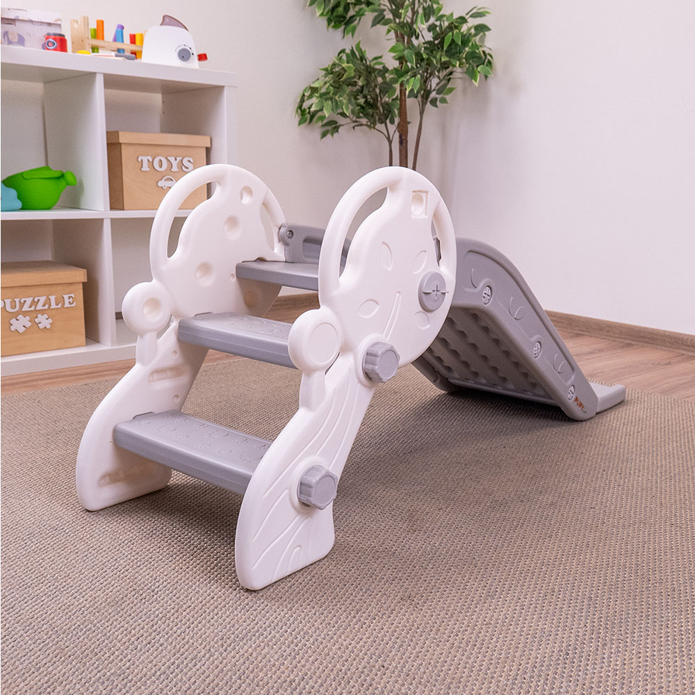Escorrega Infantil PUPY Para Interior e Exterior Escorrega infantil de plástico branco e cinzento numa sala com carpetes e prateleiras