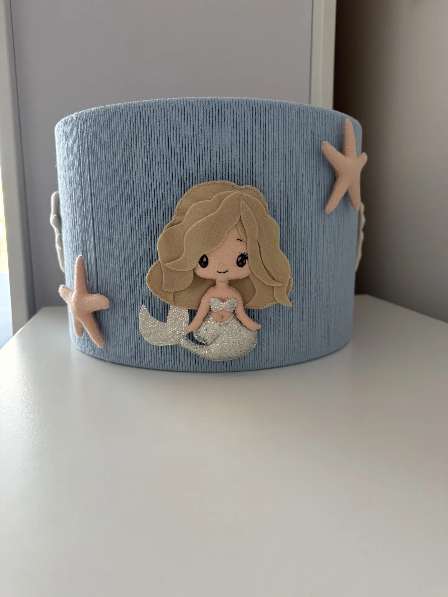 Abajur Infantil - A Pequena Sereia Cesto azul claro de tecido com decoração de sereia e estrelas-do-mar de feltro