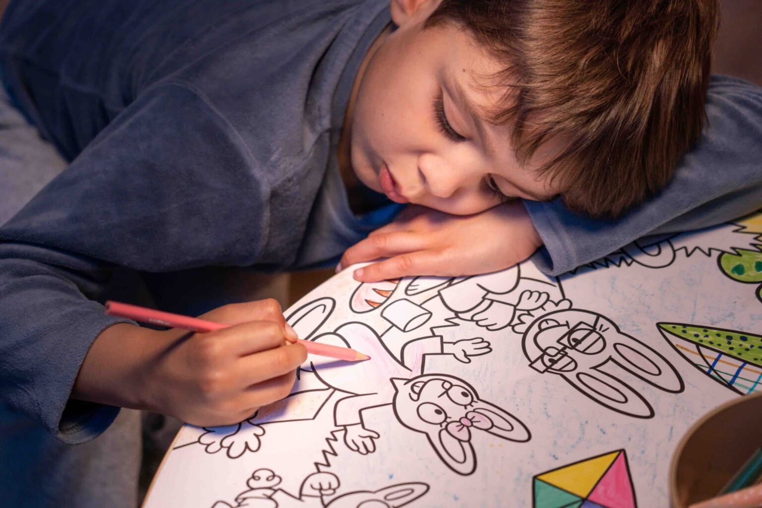 Recarga de Folhas para Colorir - Coelhinhos Criança a colorir desenho com lápis em mesa com ilustrações de animais e formas