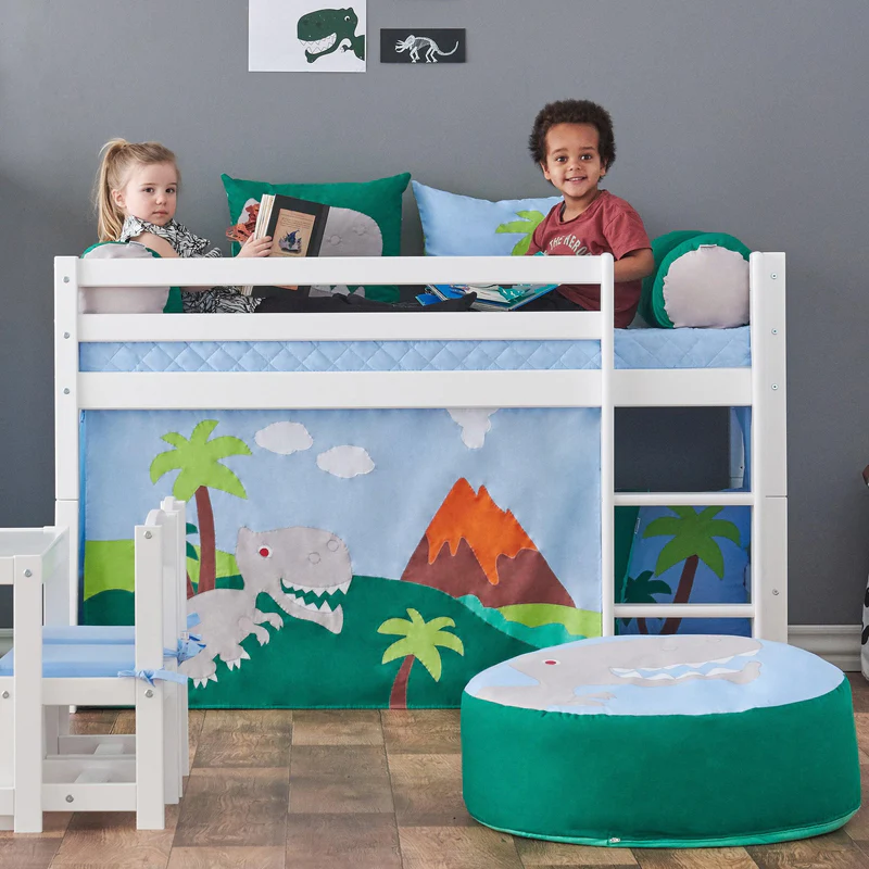 Cortina de Cama Eco Dream – Dino Cama alta de criança com tema dinossauro, cadeirinha infantil e puff, duas crianças na cama, parede cinzenta com quadros de dinossauros