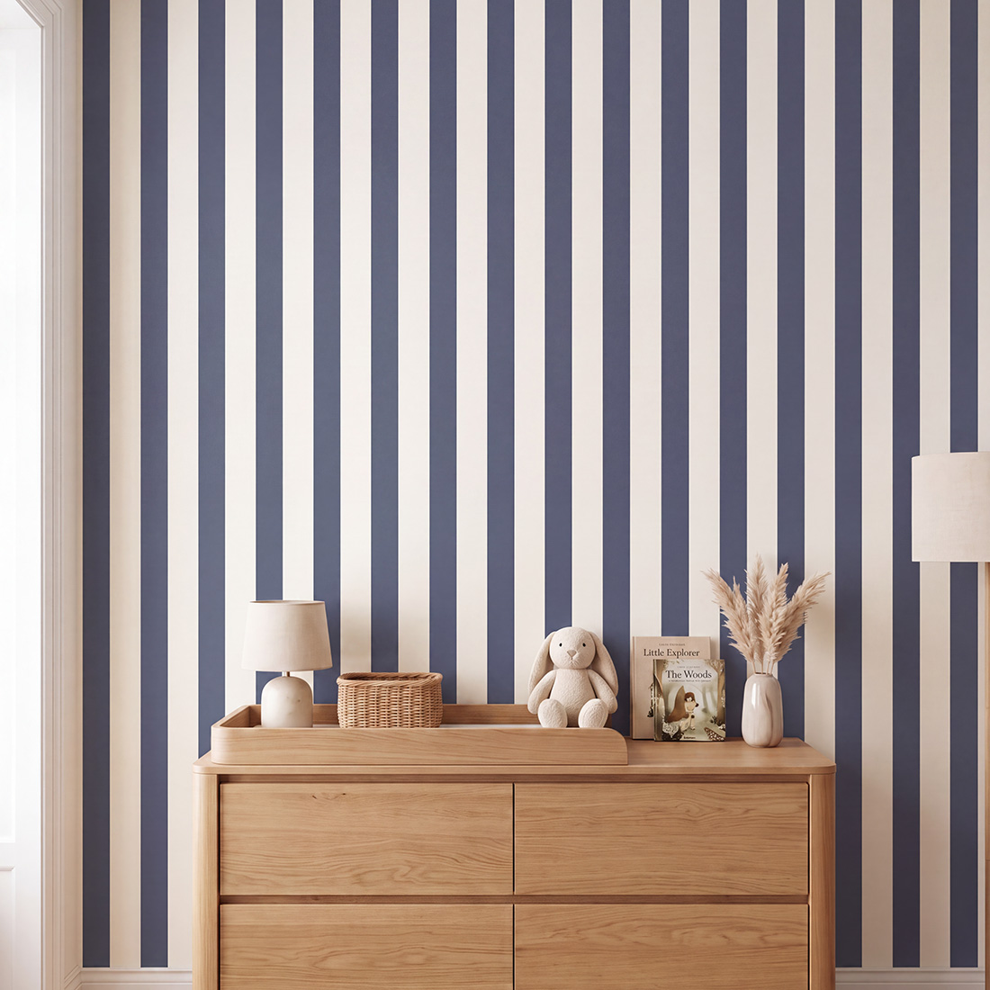 Papel de Parede Infantil às Listas Finas Cómoda de madeira clara com objetos decorativos contra parede de riscas verticais azul e branco