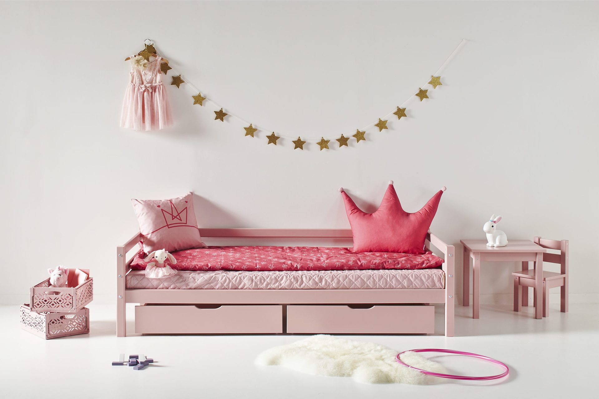 Almofadas Decoração Princesa Quarto infantil com cama rosa, almofadas, mesa e cadeira de criança, vestido cor-de-rosa e decoração de estrelas.