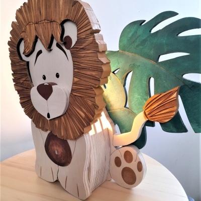 Leão decorativo de madeira pintada com juba castanha e folha verde ao fundo