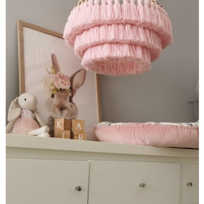 Lustre rosa de franjas suspenso em quarto infantil com decoração de coelho e blocos de madeira
