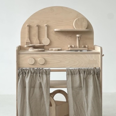 Cozinha infantil de madeira clara com utensílios, torneira e cortinas xadrez