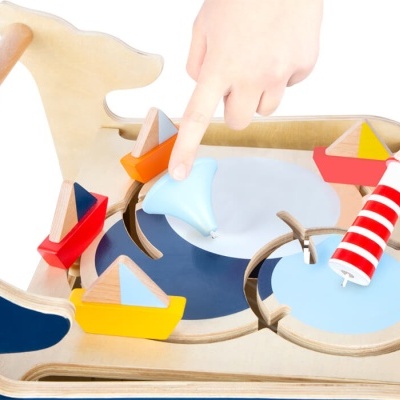 Brinquedo de madeira em forma de vaca com barcos e farol coloridos de madeira.